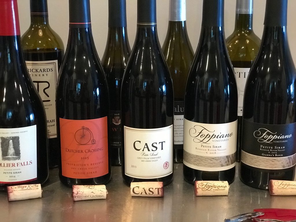 Bottles of Petite Sirah on a table with corks
