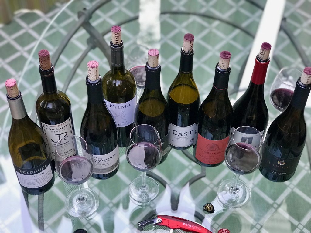 A wide selection of Petite Sirah on a glass table looking down from above.