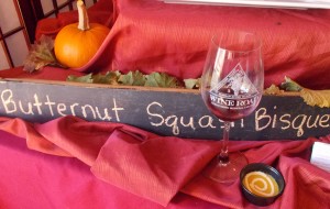 Sign for Butternut Squash Bisque with wine glass and sample of the bisque