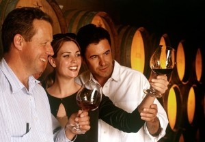 Three people in a wine cellar looking at the wine in their glasses