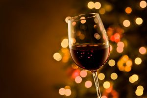Glass of red wine with Christmas lights behind