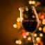 Glass of red wine with Christmas lights behind