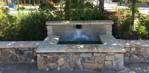 water feature and stone bench along the sidewalk