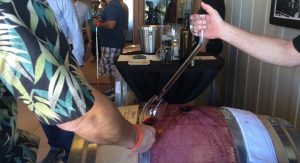 Wine being poured from a glass barrel thief into a wine tasters glass.