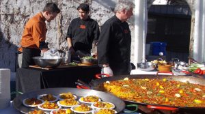 Paella being cooked and served at a winery event.