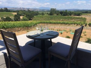 Table and chair on a patio set up for a private tasting overlooking vineyards.