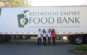 Redwood Empire Food Bank semi-truck with four people standing below the side of the truck.