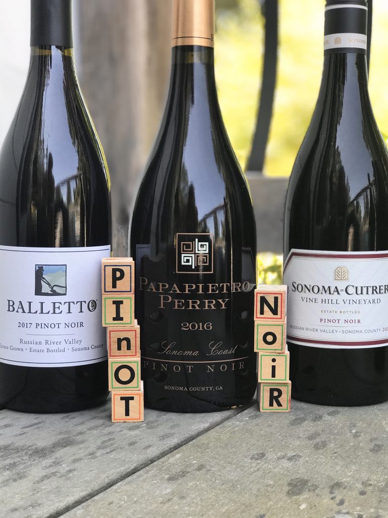 Bottle of Pinot Noir Balletto_Papapaierto_Perry_Sonoma_Cutrer on a deck with letter blocks