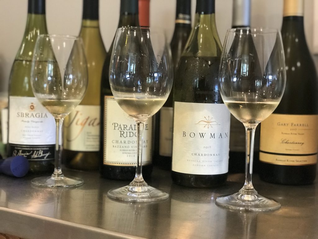 Chardonnay in glasses on a counter-with bottles blurred in the background