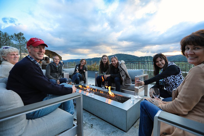 Guests gather around the fire pit on the deck at Trattore Farms Estate Wines tasting room.