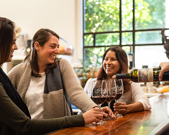 Three woman having wine poured for them at the Dry Creek Vineyard tasting room.