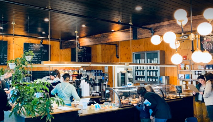 Plank Coffee shop with pastry case and barista's in background