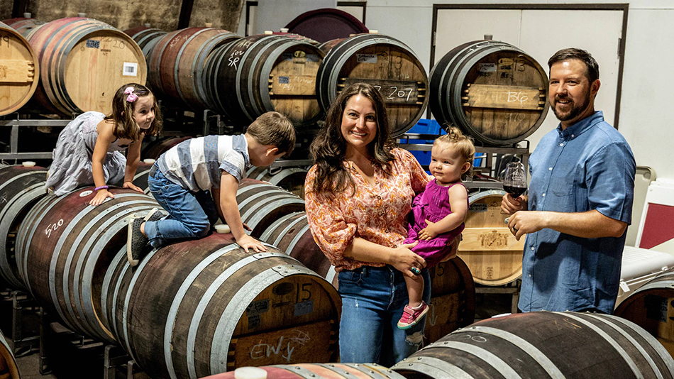 April and Andrew Nalle with their three kids among the barrels of wine.
