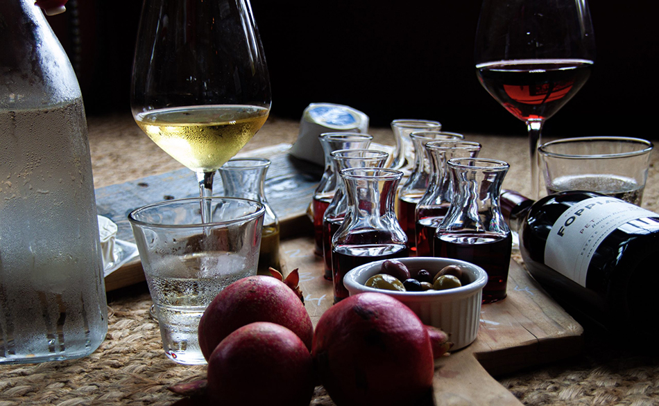 A tasting flight of Foppiano wines with little carafes of tastes with olives, cheese, poured glasses of wine, water glasses, and a bottle of Foppiano Petite Sirah laying on its side.