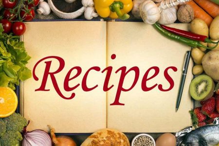 Recipes written large on an open book with various ingredients forming a frame around the open book.