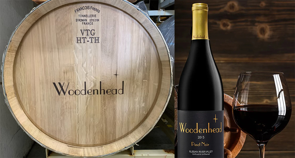 Wine barrel head with Woodenhead's logo and bottle of Woodenhead 2015 Pinot Noir next to a glass of red wine.