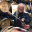 Carol Shelton pouring wine from a barrel using a wine thief into a Wine Road wine glass. Barrels in the background with Carol Shelton Wines stamped on each barrel.