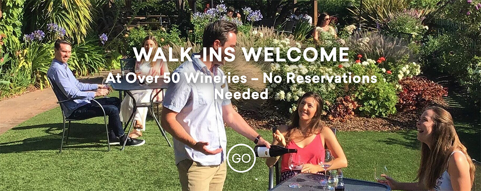 Text is Walk-ins Welcome at over 50 wineries - no reservations needed. Background image of young people tasting wine in a garden setting as server is pouring the wine.