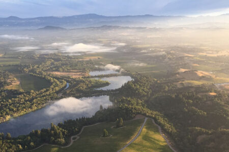 Aerial view of Russian River Valley showing the fog heaviest over the river and then drifting over the surrounding land.